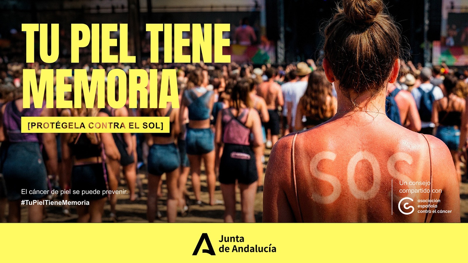 Campaña de la Junta de Andalucía y la Asociación Española Contra el Cáncer sobre prevención solar, con el lema "Tu piel tiene memoria. Protégela contra el sol". La imagen muestra la espalda quemada por el sol de una persona en un festival, con las letras SOS marcadas en la piel. Hashtag: #TuPielTieneMemoria.